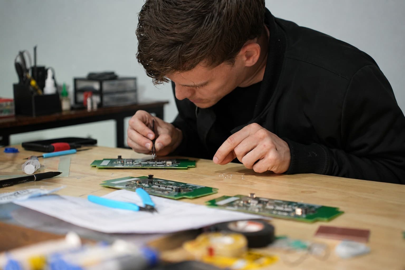The founder at a workbench, probing a WarpKVM circuit board surrounded by tools