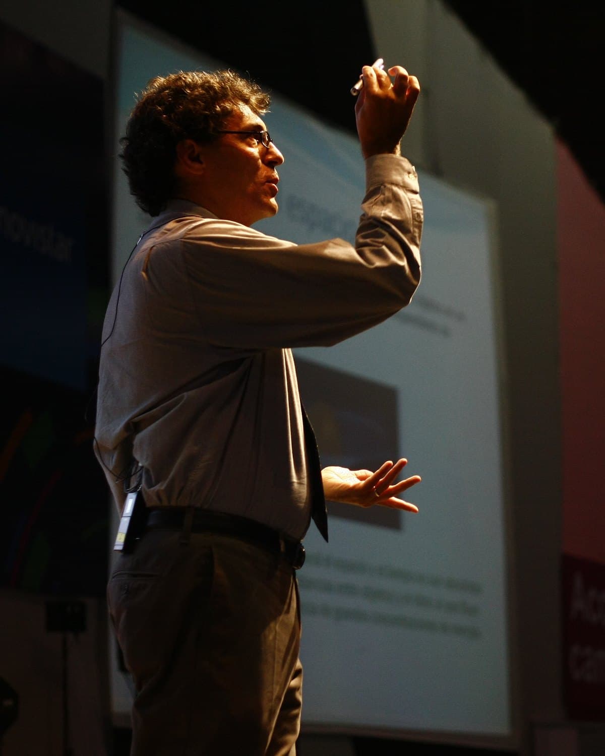 Miguel Alcubierre lecturing on stage, mid-gesture, dramatically lit