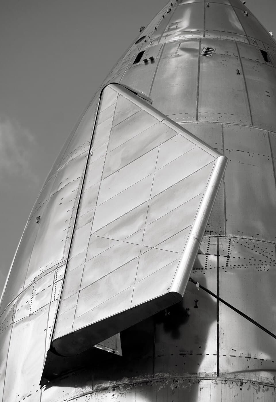 Close-up of a Starship prototype's stainless steel aft flap, riveted panels catching the light